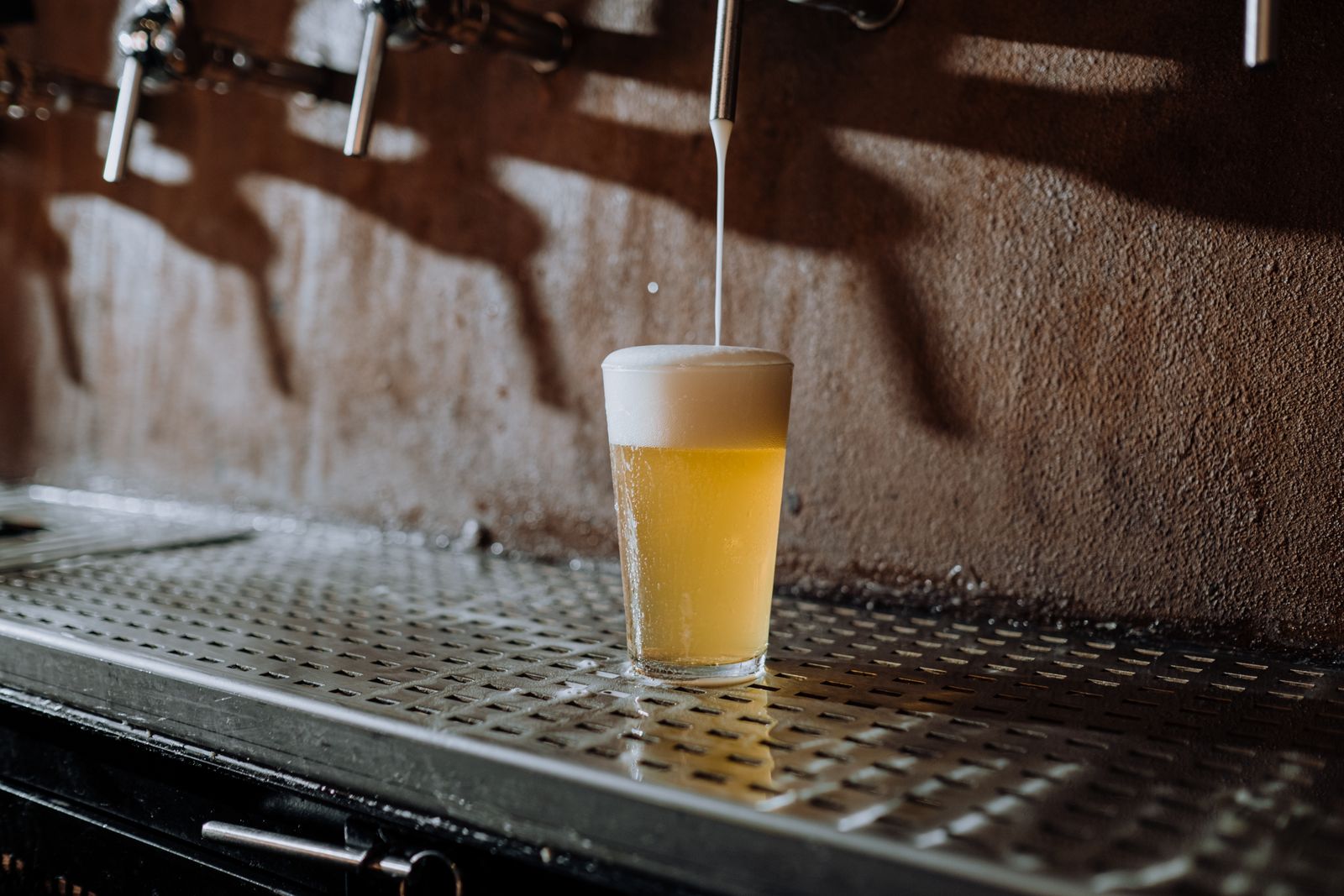 Bière blonde tirée à la pression, mousse débordante