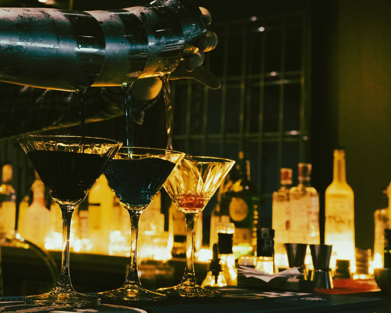 Cocktails ambrés alignés sur le comptoir à la lueur des bougies