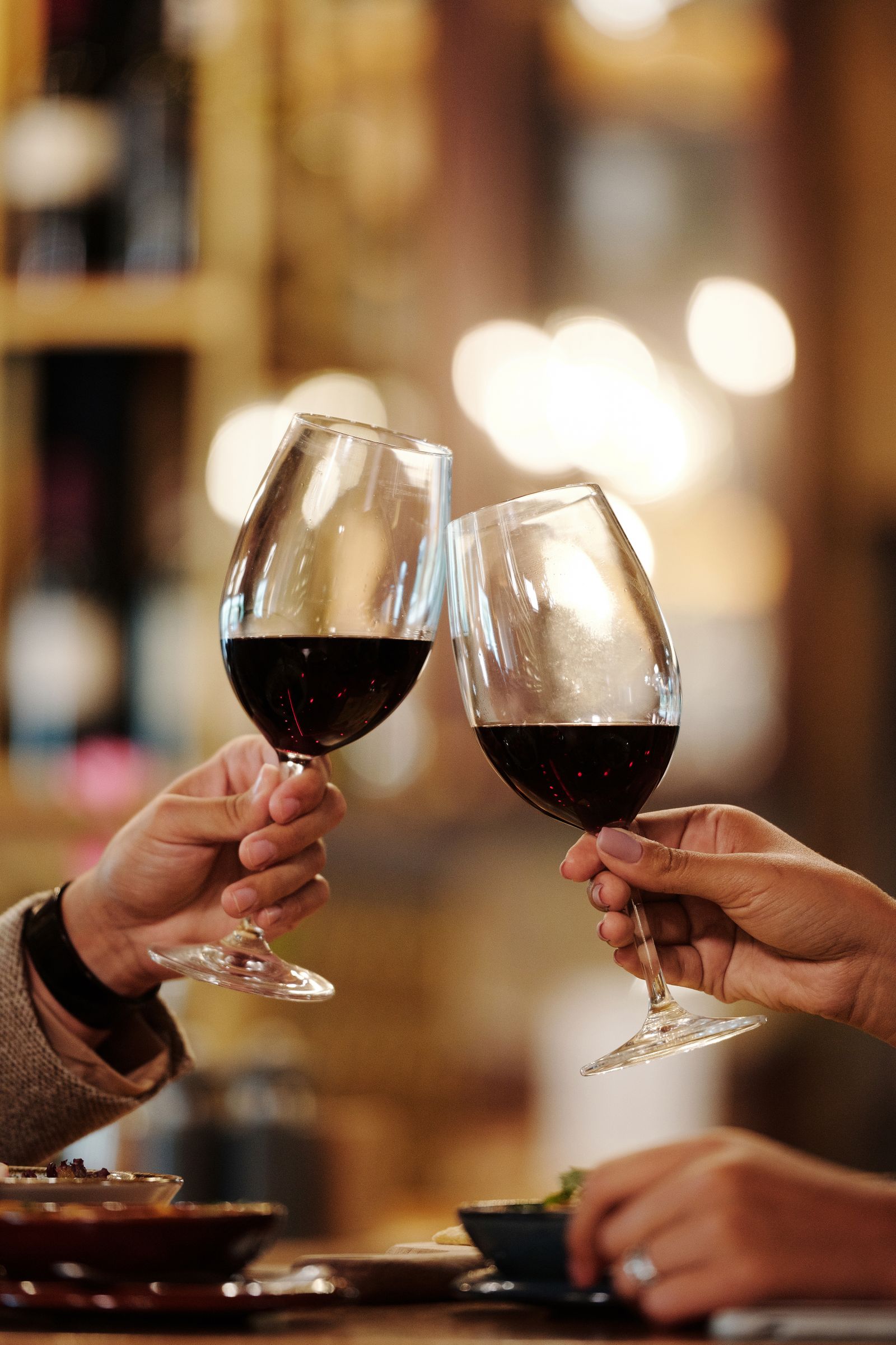 Deux verres de vin rouge trinquent à la lumière du comptoir