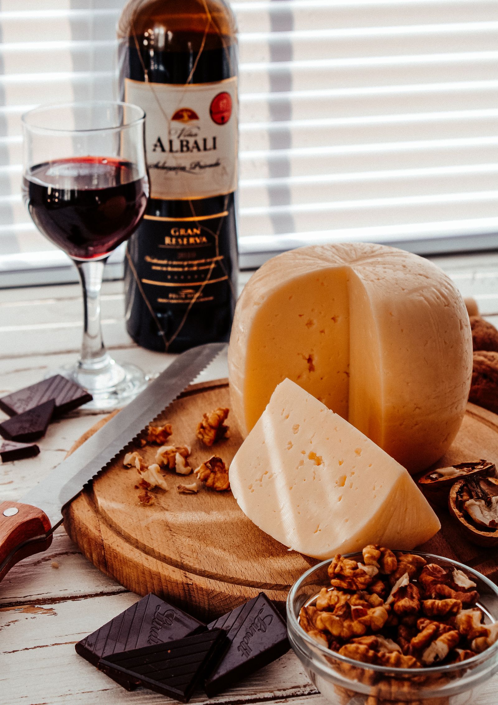 Bouteille de vin rouge et fromages sur planche de bois