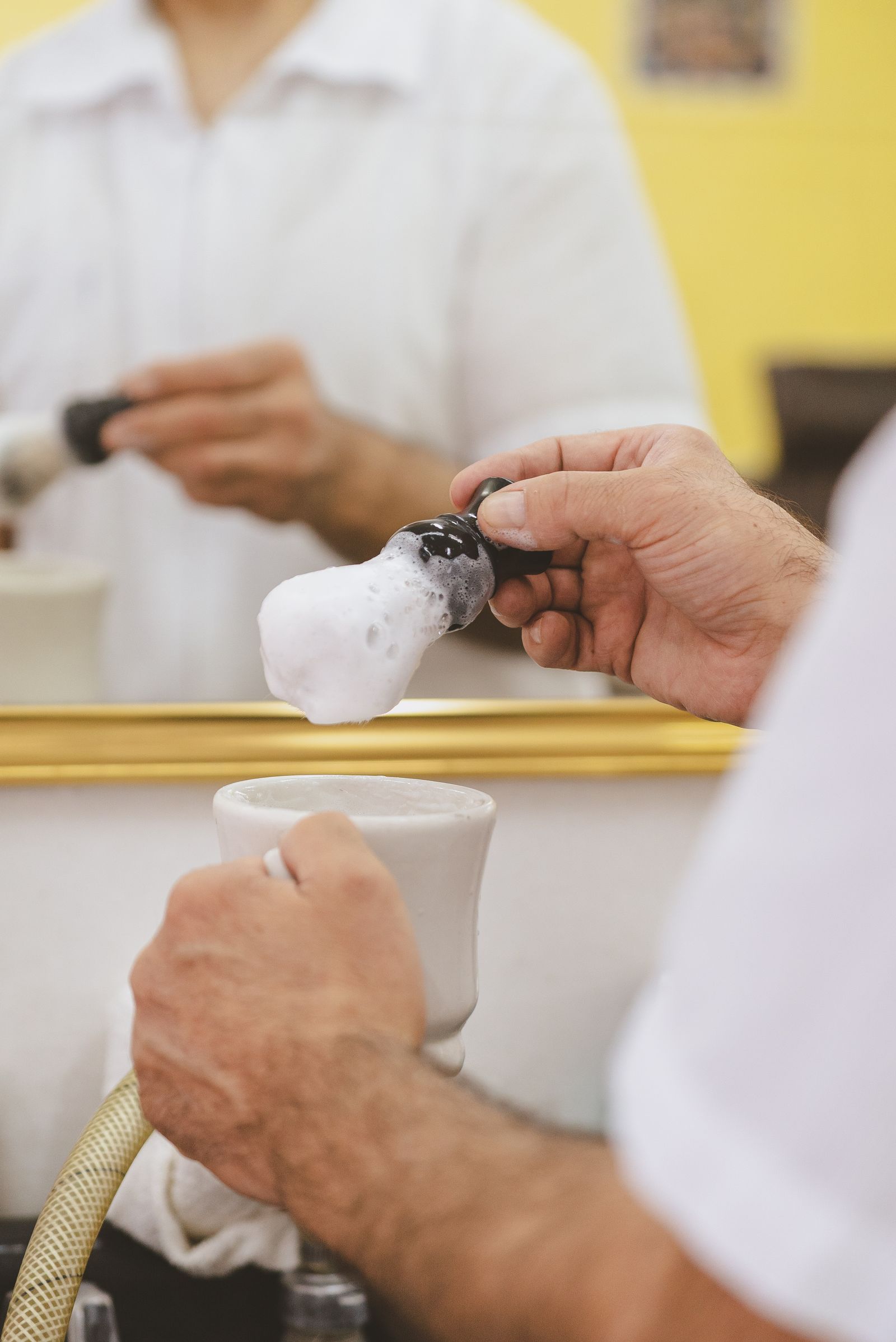 Le barbier monte la mousse au blaireau dans le bol