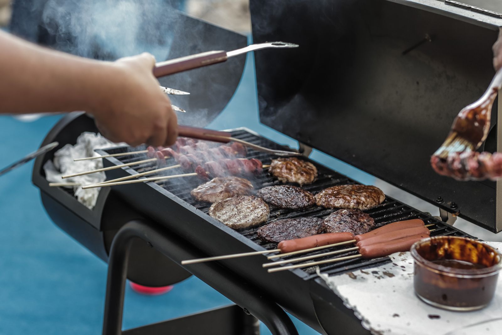 Les mains du grillardin au-dessus du brasero, dans la fumée