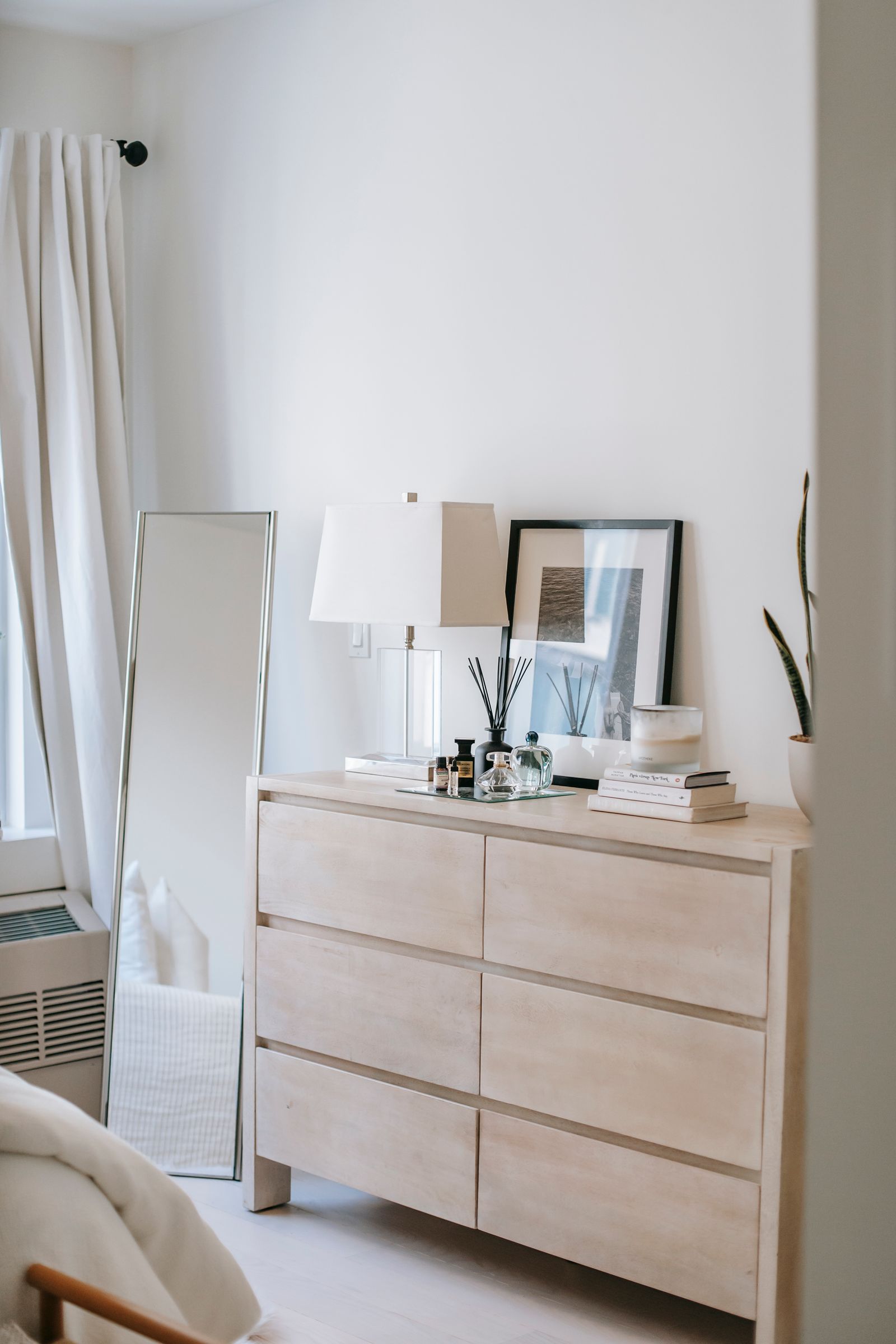 Commode claire, miroir sur pied et objets choisis sur fond clair