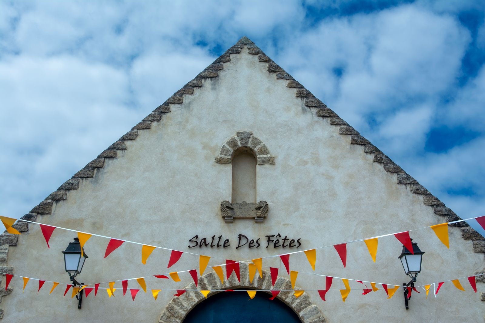La façade de la salle des fêtes pavoisée pour la fête locale