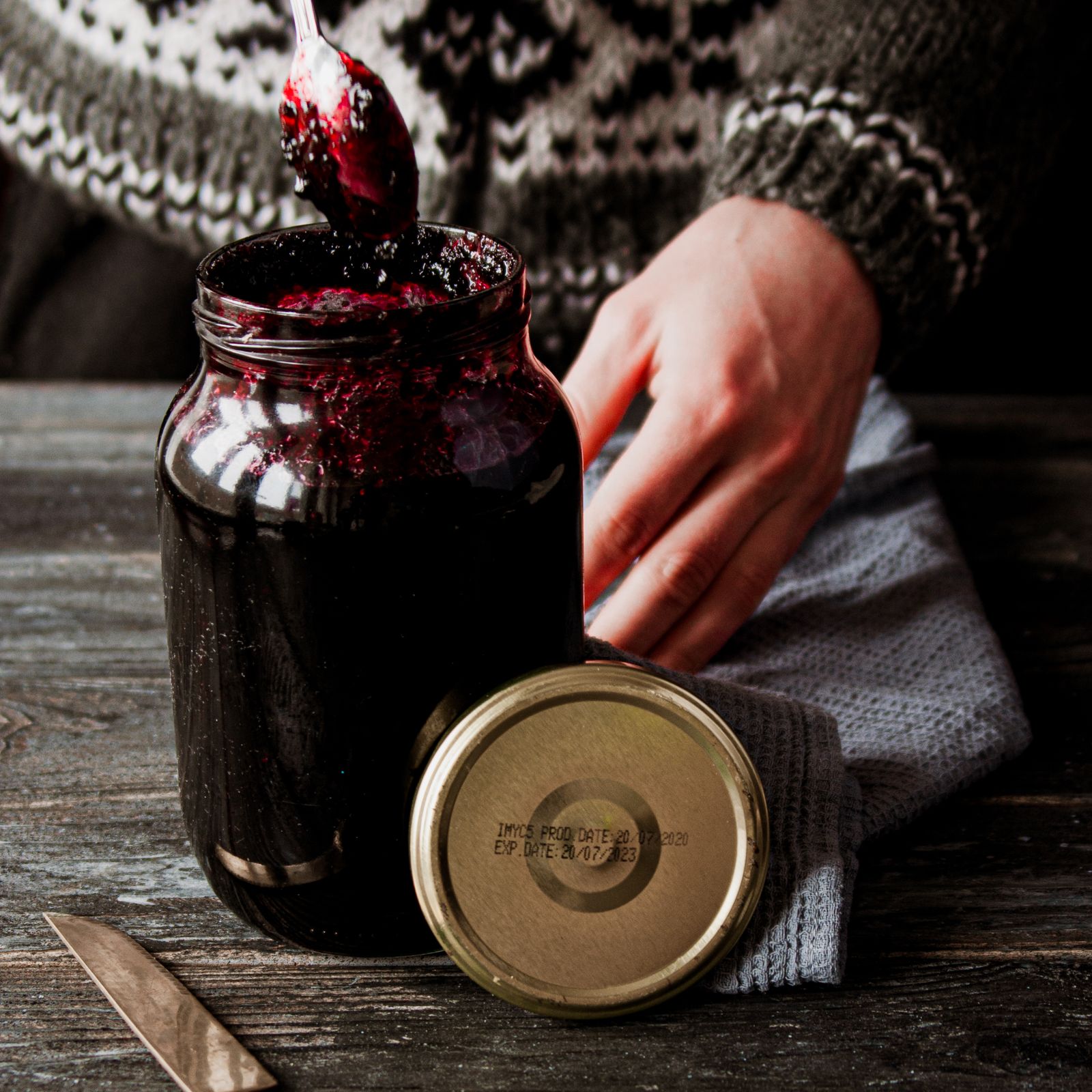 Bocal de confiture de prunes fermé à la main dans la cuisine de la maison