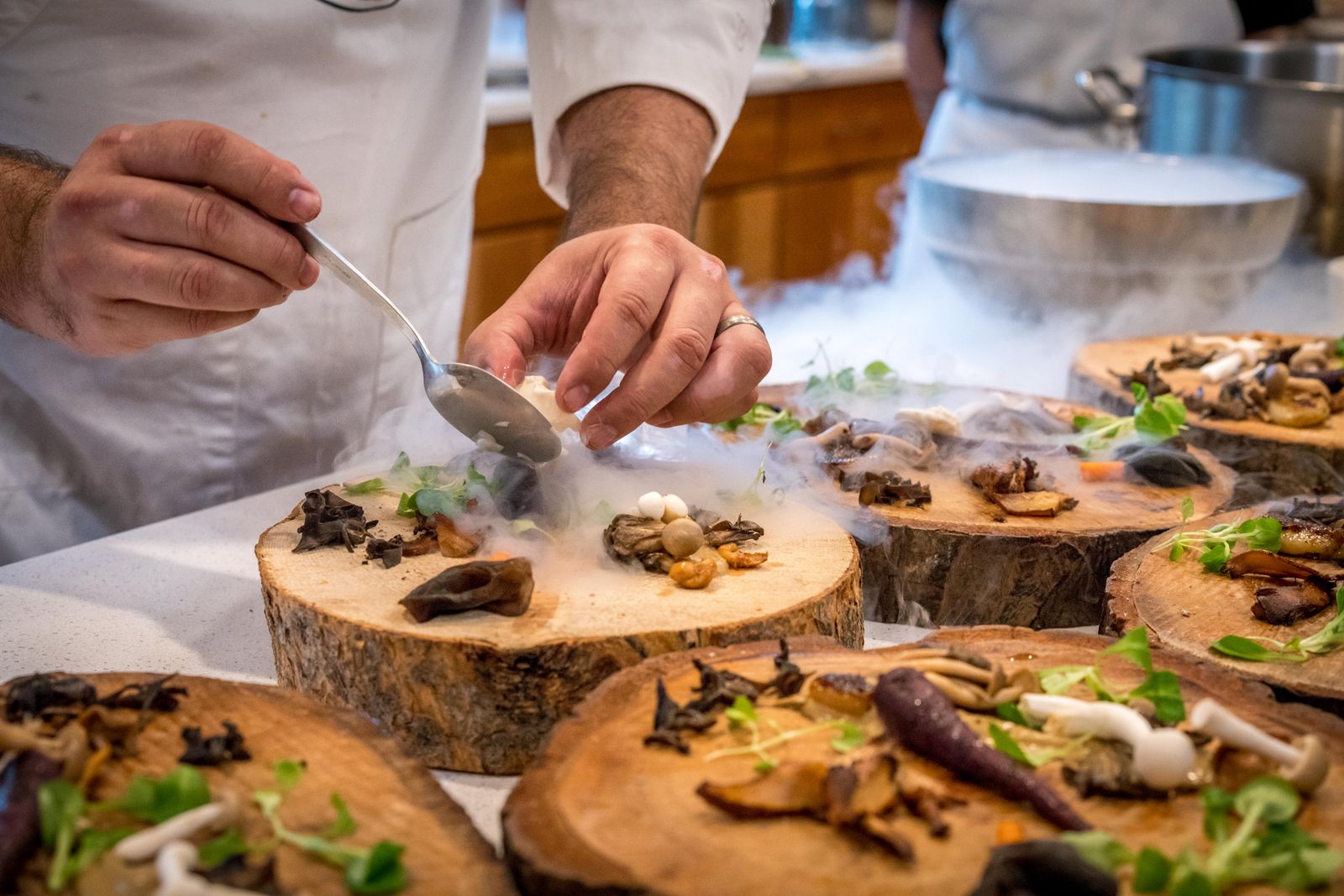 Mains du chef dressant les assiettes sur billots de bois